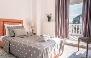 Ein Schlafzimmer mit Bett, Nachttisch, Lampe, Heizkörper und Blick ins Freie.