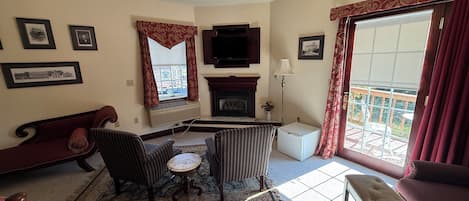 Un salon avec une cheminée, un téléviseur et un balcon offrant une vue dégagée.