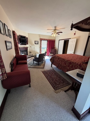 Une chambre d’hôtel équipée d’un lit, d’un canapé, d’un bureau, d’une chaise, d’une télévision et d’un ventilateur de plafond.