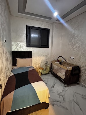 A bedroom with a bed, a window, a vanity, and a small toy car.