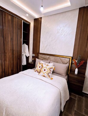 A bedroom with a bed, a wardrobe, and a nightstand with a vase.