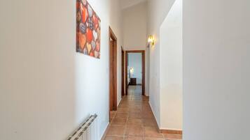 Un pasillo con suelo de baldosas, un cuadro en la pared y una puerta que da a otra habitación.