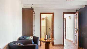 Una habitación con un sofá, una mesa redonda de madera con velas y una puerta que da a un baño.