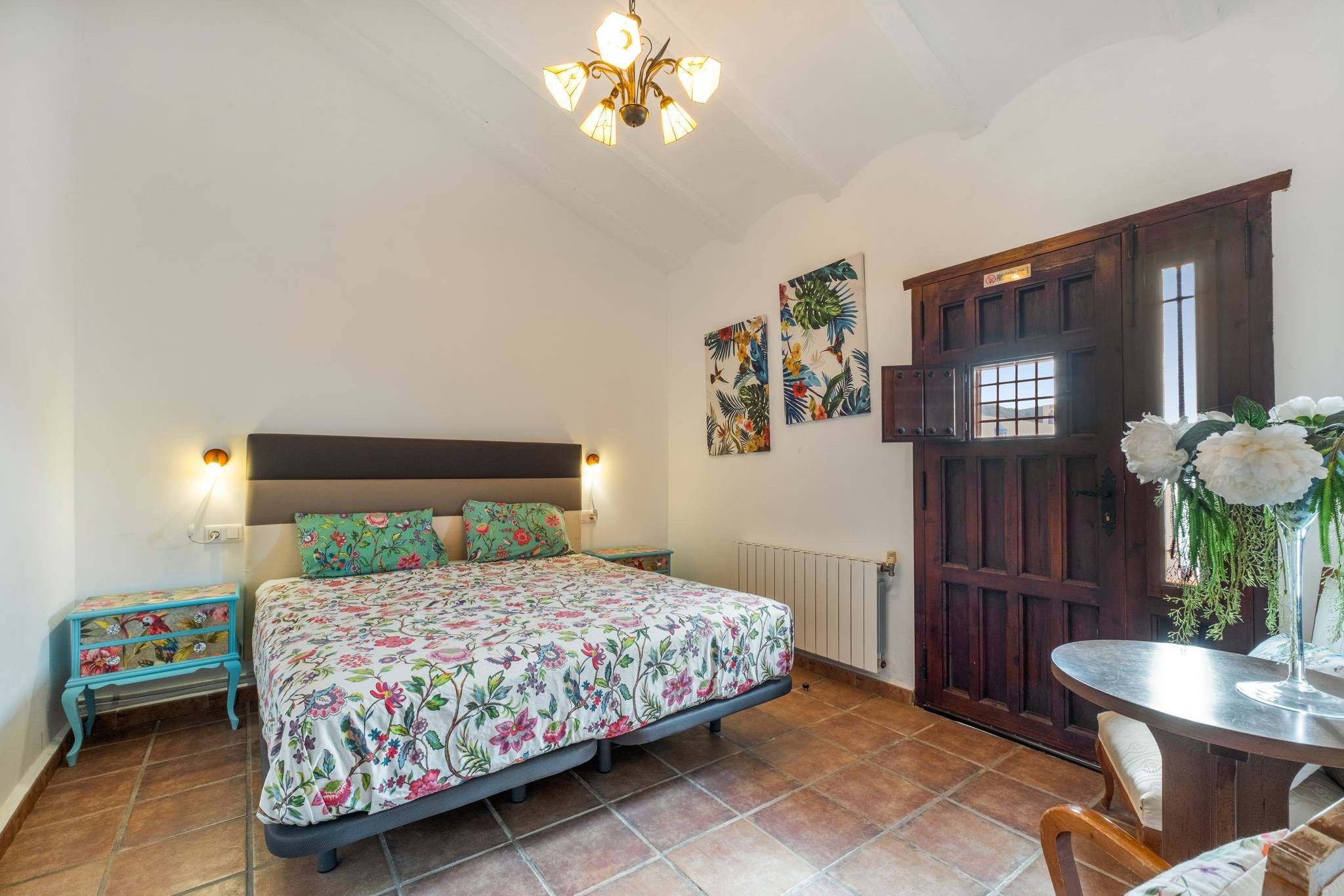 Un dormitorio con cama, mesita de noche, cómoda, puerta y ventana.