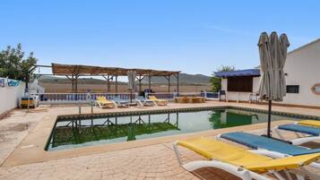 A swimming pool with lounge chairs and a pergola.