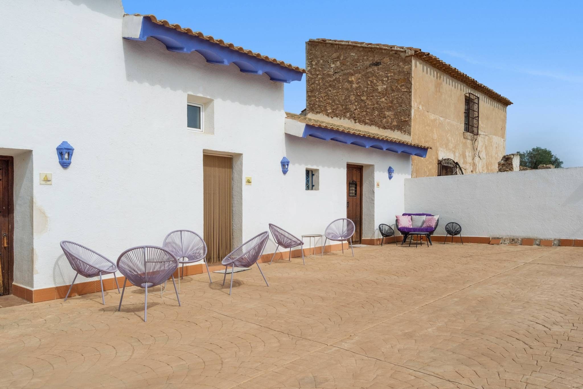 Un patio con mesas al aire libre y un edificio con techo de tejas.