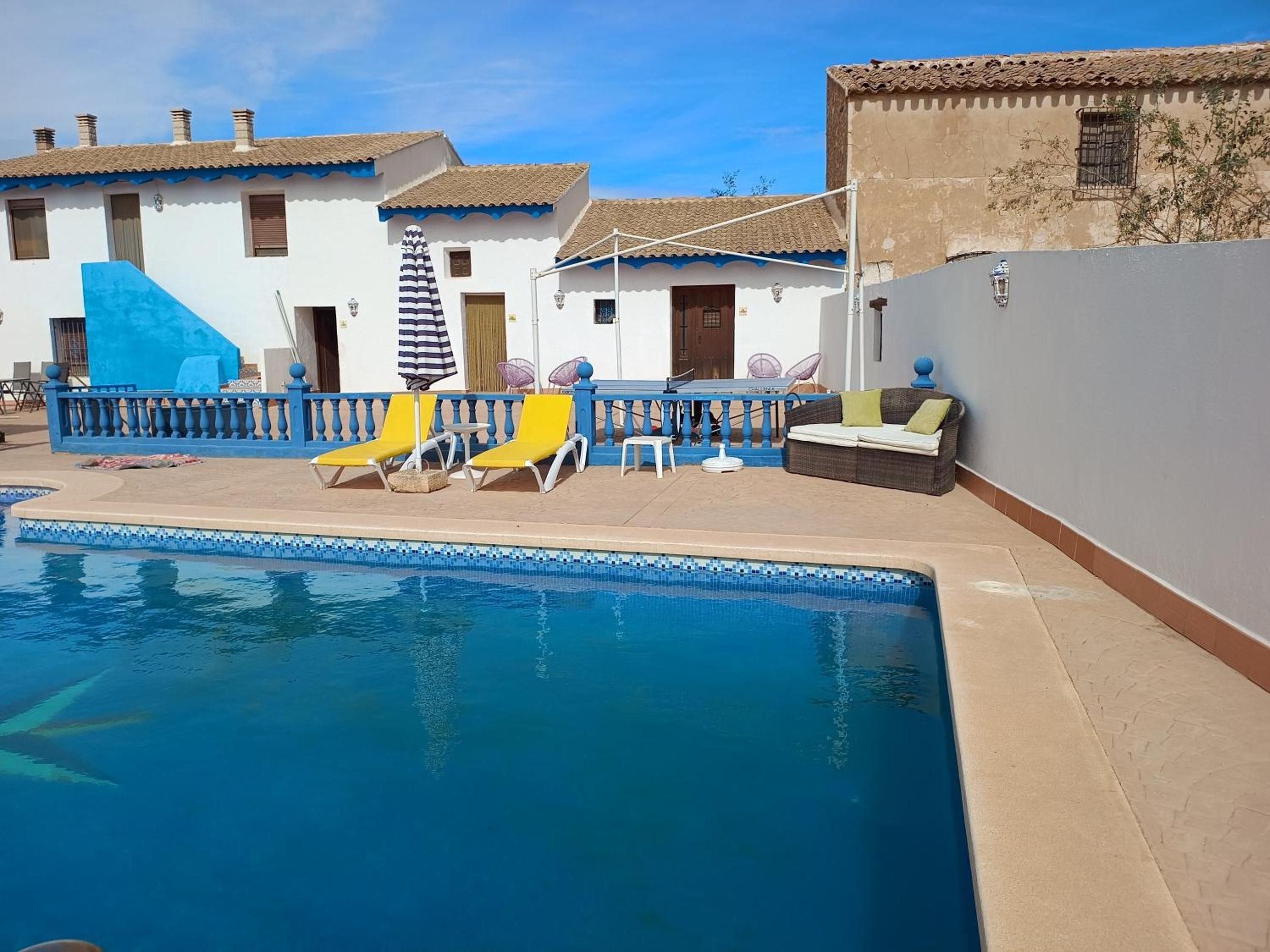 A pool area with lounge chairs, a table, and a small seating area.