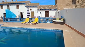 A pool area with lounge chairs, a table, and a small seating area.