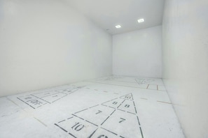 A room with white walls and a tiled floor marked with numbers and lines, likely for a game or activity. - Bluewater Resort 819- Side Ocean View 1BR- Pool (Myrtle Beach)