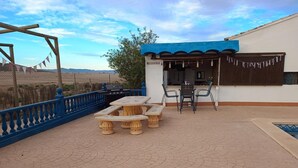 Une terrasse extérieure équipée d’un barbecue, d’une table avec des chaises et d’un espace piscine.