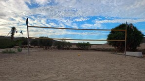 Un filet de volley-ball installé sur une surface sablonne, avec un ciel dégagé en arrière-plan.