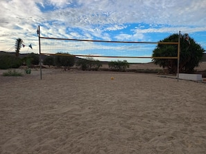 Een volleybalnet op een zandige ondergrond, met een heldere lucht op de achtergrond.