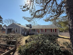 A two-story house with a garage, a front porch, and a fenced yard. - NEW in 2026: Cozy Oasis- great backyard, near Dennis Beaches, Great Restaurants (Dennis)