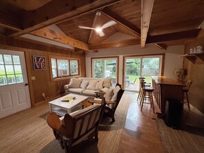 A cozy interior with a wooden ceiling, a sofa, a dining table, and a kitchen area. - NEW in 2026: Cozy Oasis- great backyard, near Dennis Beaches, Great Restaurants (Dennis)