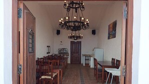 A dining area with wooden tables and chairs, a chandelier, and a door leading to another room. - Room 'Calabaza' with Mountain View, Wi-Fi and Air Conditioning (Lorca)