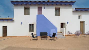 A building with a blue accent wall, multiple windows, and outdoor seating with chairs and tables.