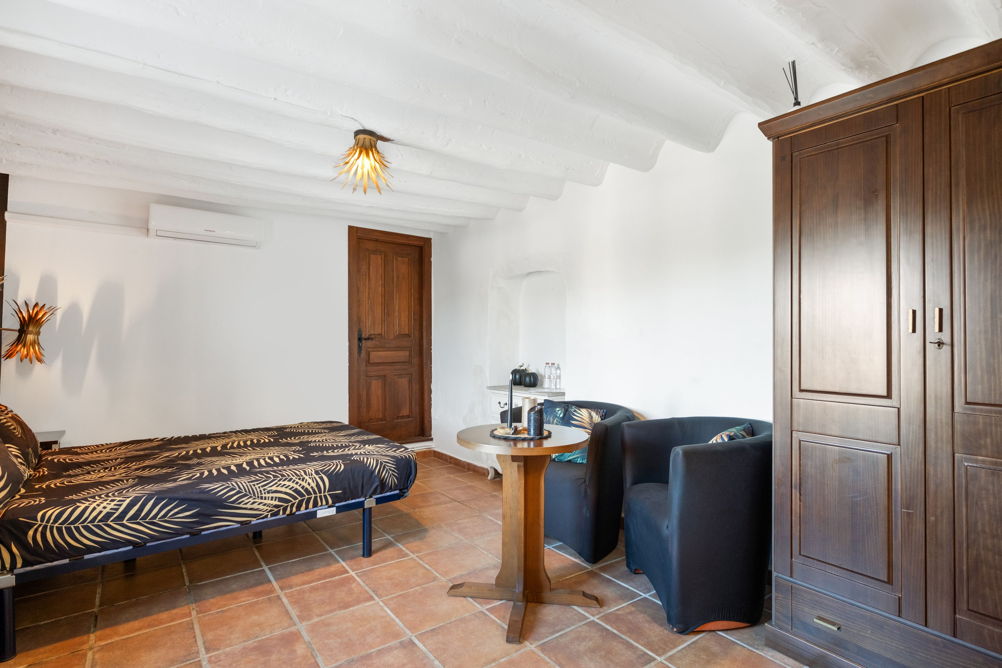 Una habitación con cama, una silla, una mesa y un armario.