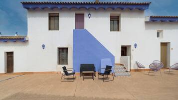 Un edificio con una pared azul de acento, varias ventanas y un área de estar al aire libre con sillas y mesas.