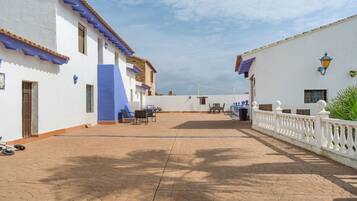 Un patio con edificios blancos, detalles azules y una cerca blanca.