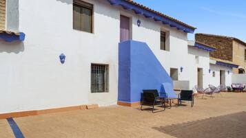 A building with a white exterior and blue accents, featuring a patio area with outdoor seating.