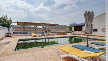 Un área de piscina con sillones de descanso y una pérgola.