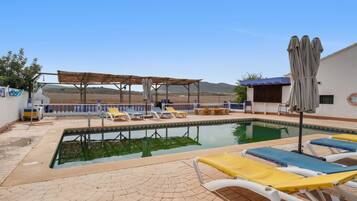 Une piscine avec des chaises longues et une pergola.