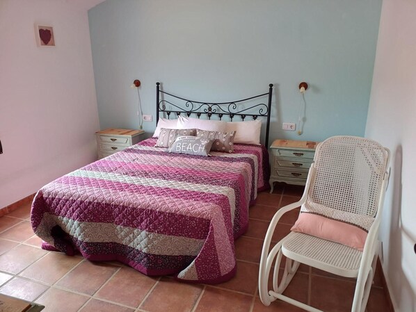 Une chambre à coucher comprenant un lit, deux tables de chevet, une chaise et un luminaire fixé au mur.