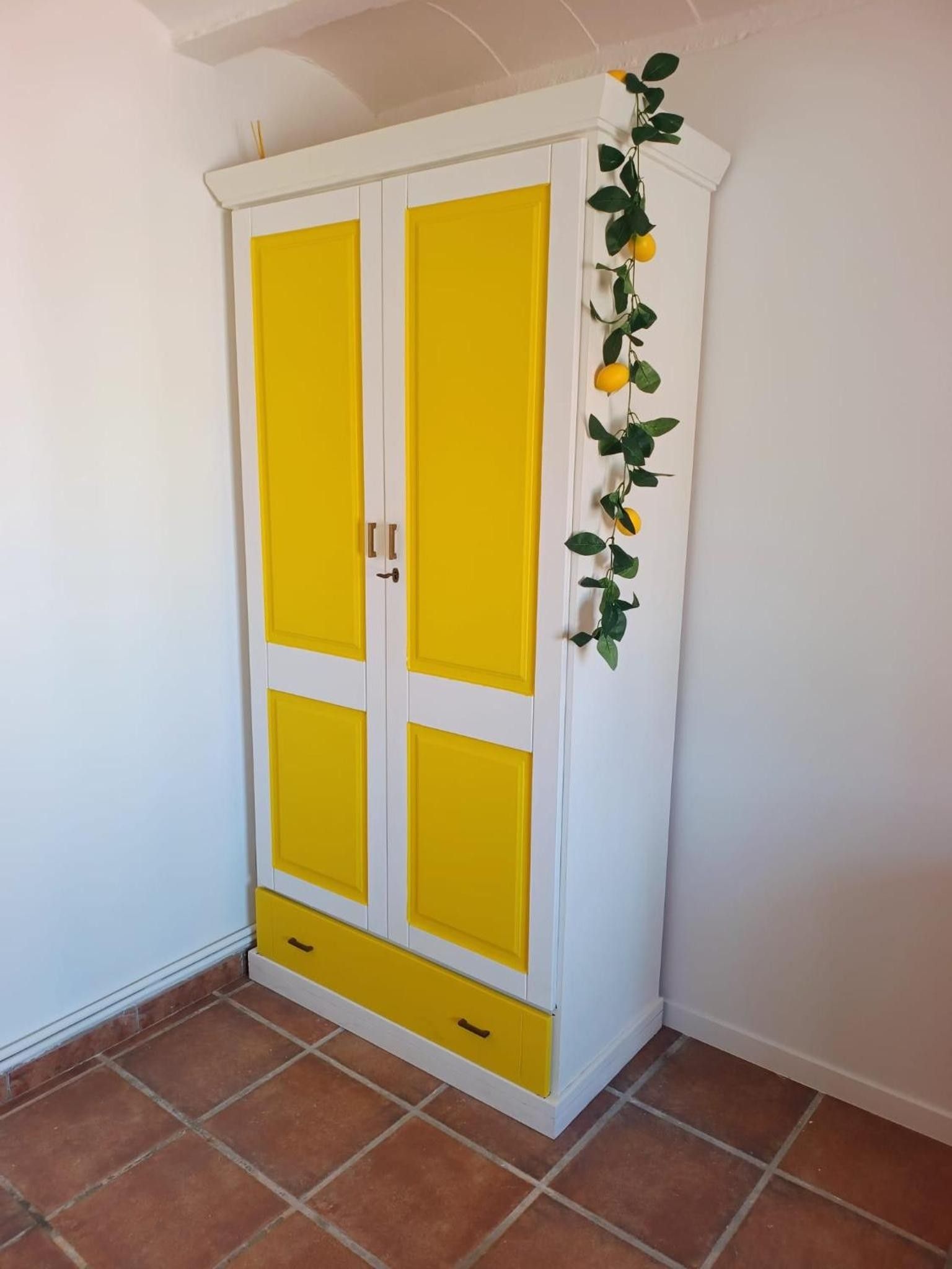 A white and yellow wardrobe with two doors and a small drawer.