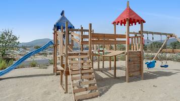 A wooden playground with a slide and climbing structures.