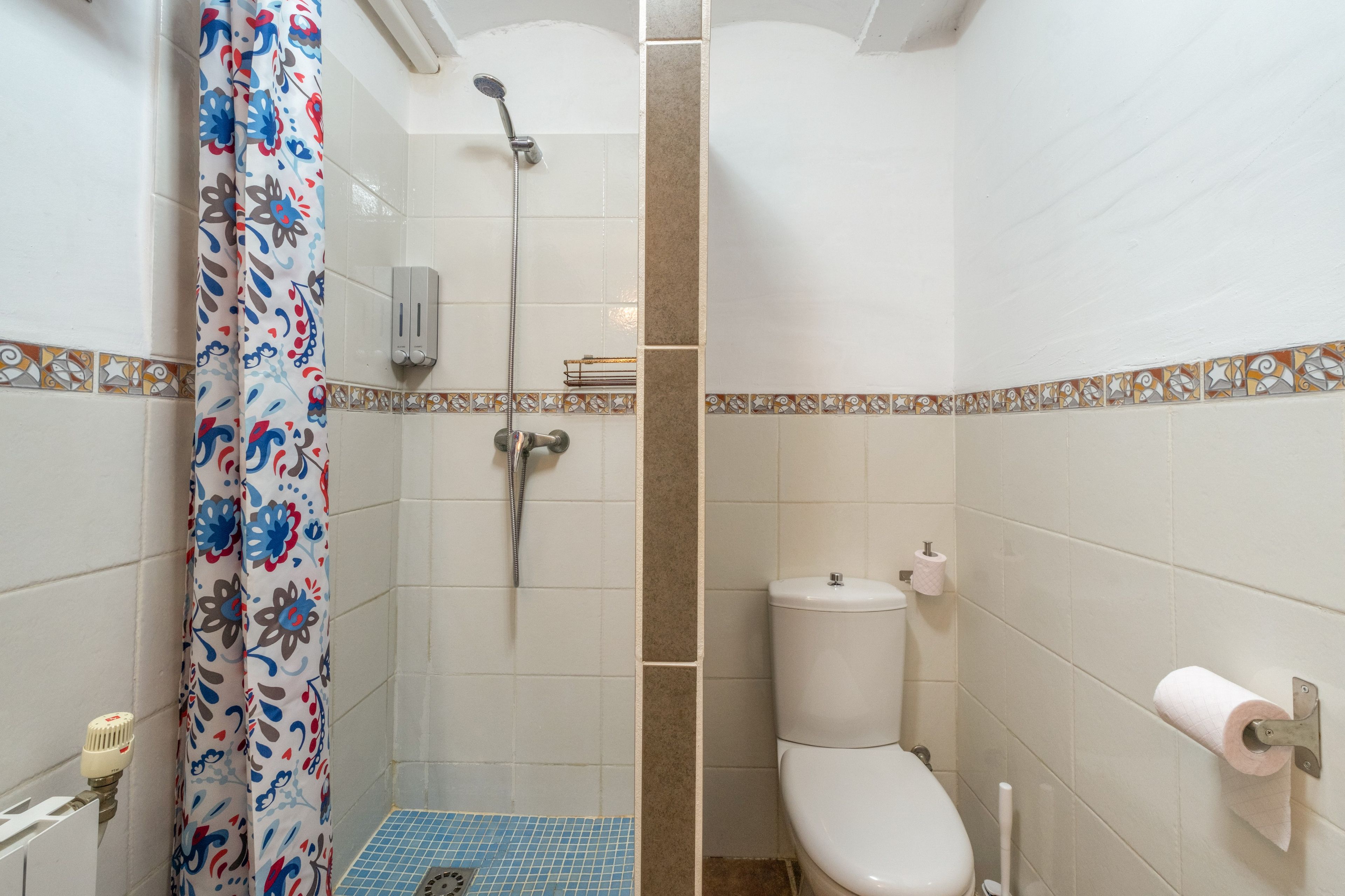 A bathroom with a shower, toilet, and a towel rack.