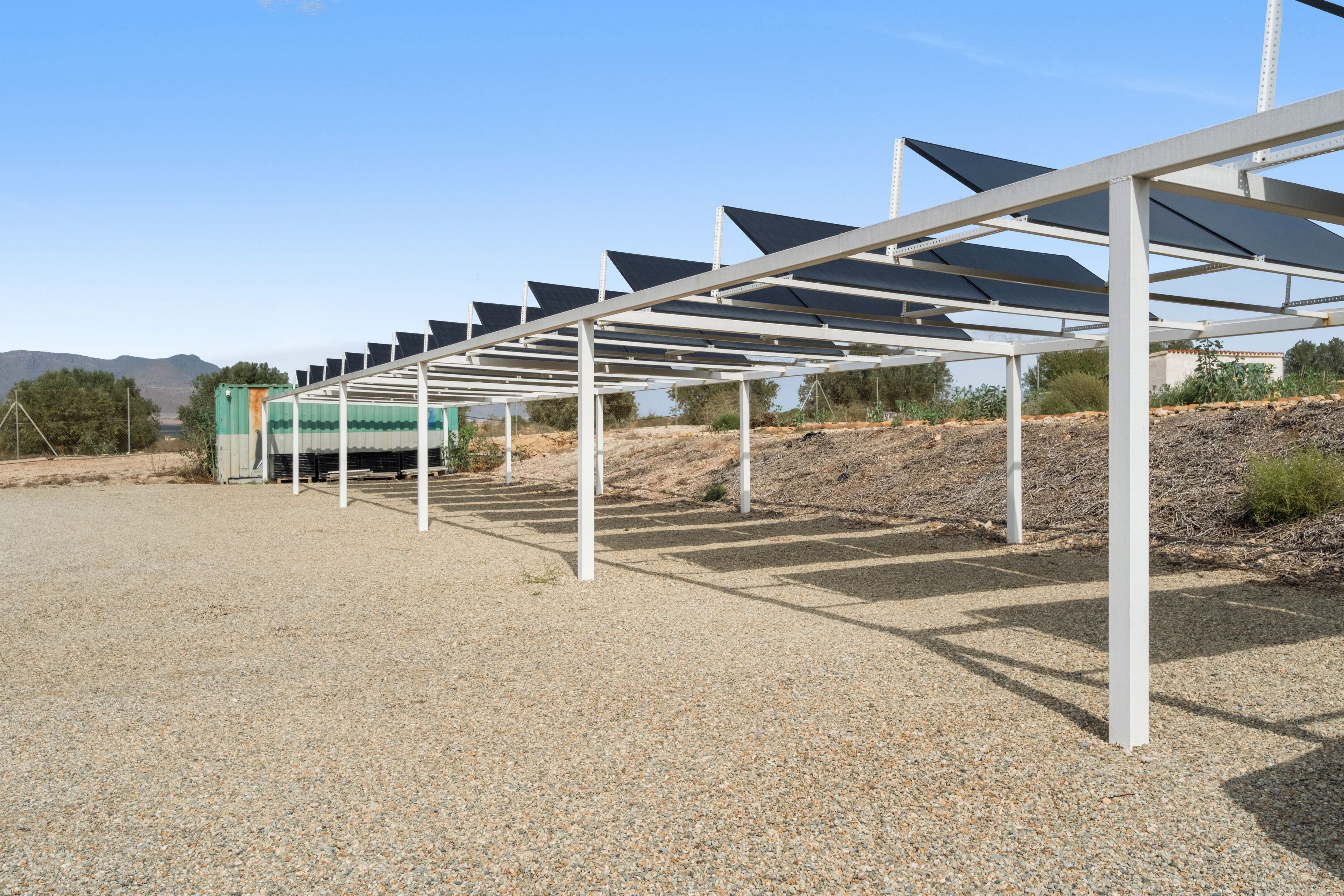 Zonnepaneleninstallatie met een metalen constructie en een grindpad.