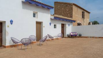 Un patio con mesas al aire libre y un edificio con toldo azul.
