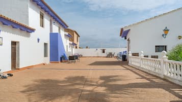 Une cour bordée de bâtiments blancs, agrémentée de touches de bleu et d’une clôture blanche.