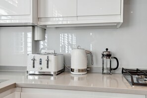 Une cuisine équipée d’un grille-pain, d’une machine à café et d’une cuisinière à gaz.