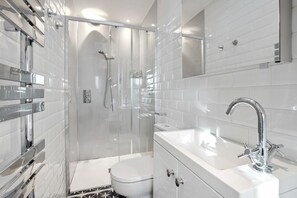 Une salle de bain moderne avec une douche à parois de verre, des toilettes blanches et un lavabo avec des finitions chromées.