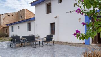 Un patio con mobiliario exterior y un edificio blanco con detalles azules.