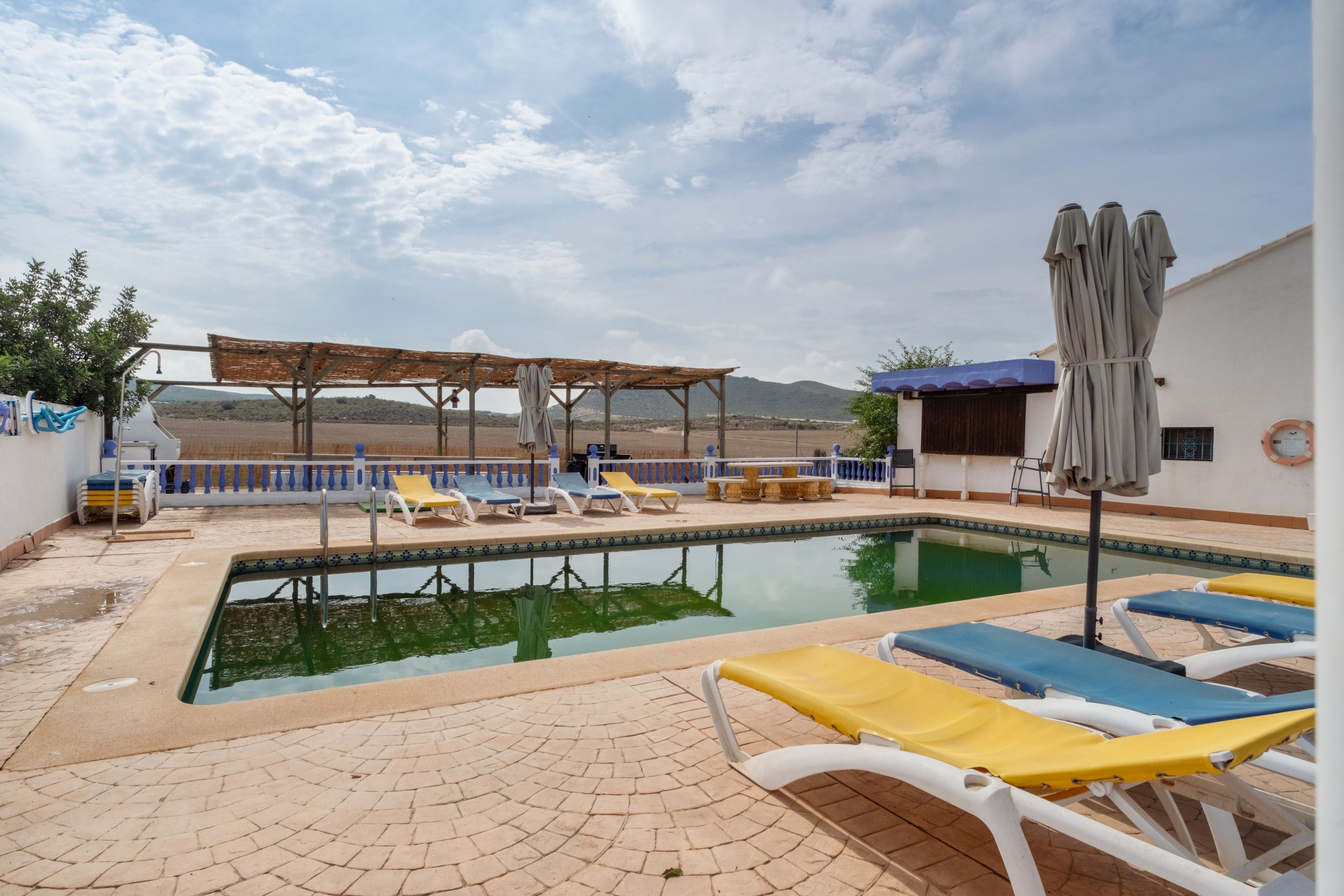 A pool area with lounge chairs and a pergola.