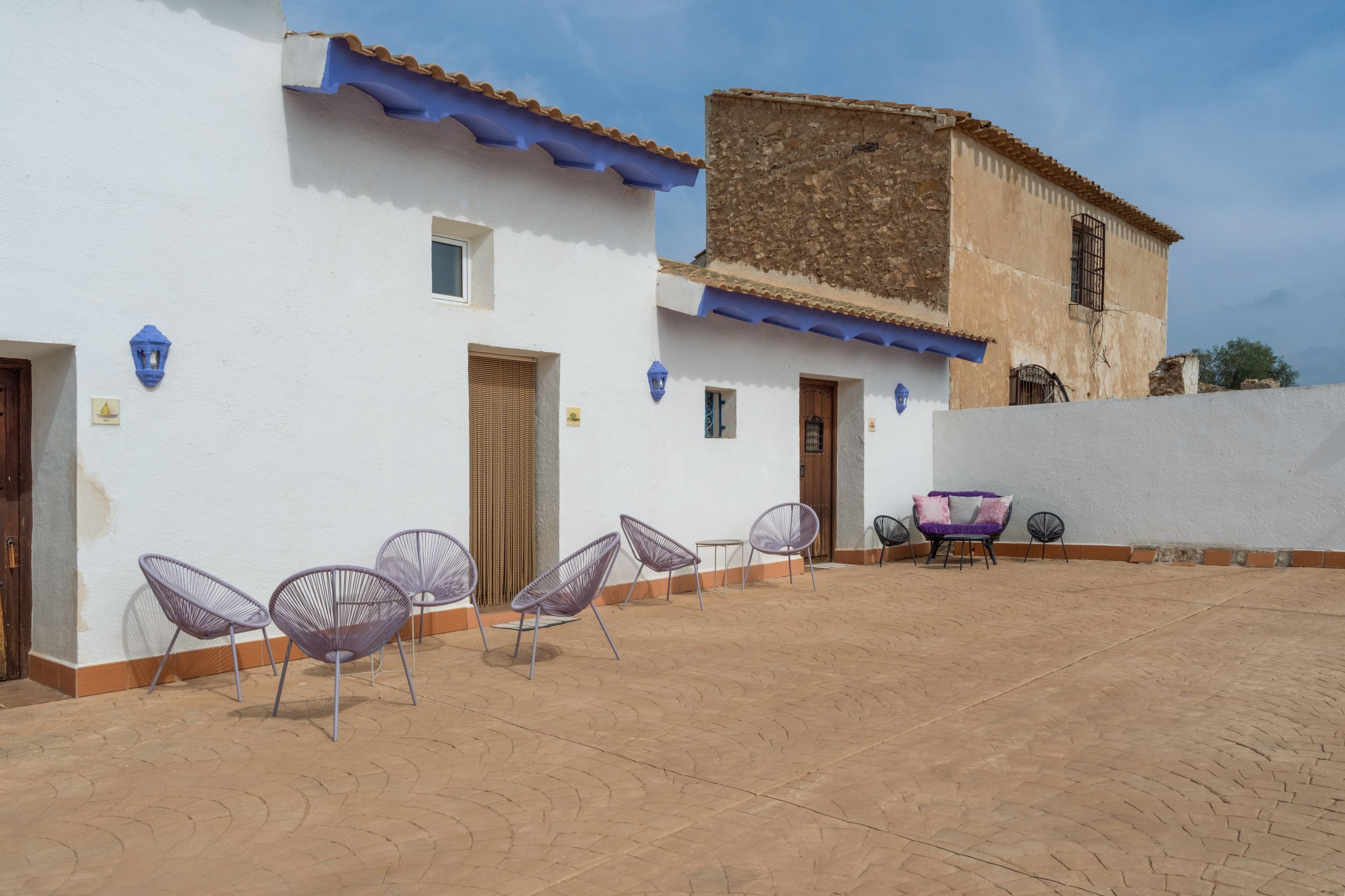 Un patio con mesas al aire libre y un edificio con toldo azul.