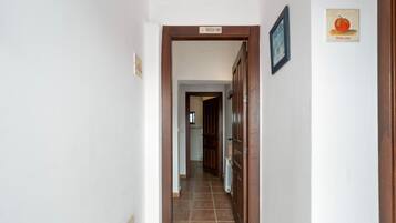 Un pasillo con una puerta de madera que indica 'PROHIBIDO FUMAR' y un cuadro con una calabaza en la pared.