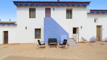 Un edificio con una pared azul de acento, un patio con sillas y un piso de baldosas.