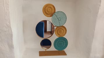 Pared con marco blanco y una instalación artística geométrica con espejos circulares y discos metálicos.