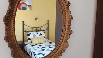 Un dormitorio con cama, un espejo en la pared y un cuadro.