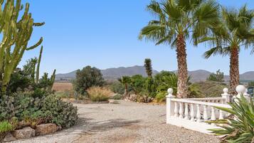 A gravel pathway leading to a white fence with a view of mountains in the distance.