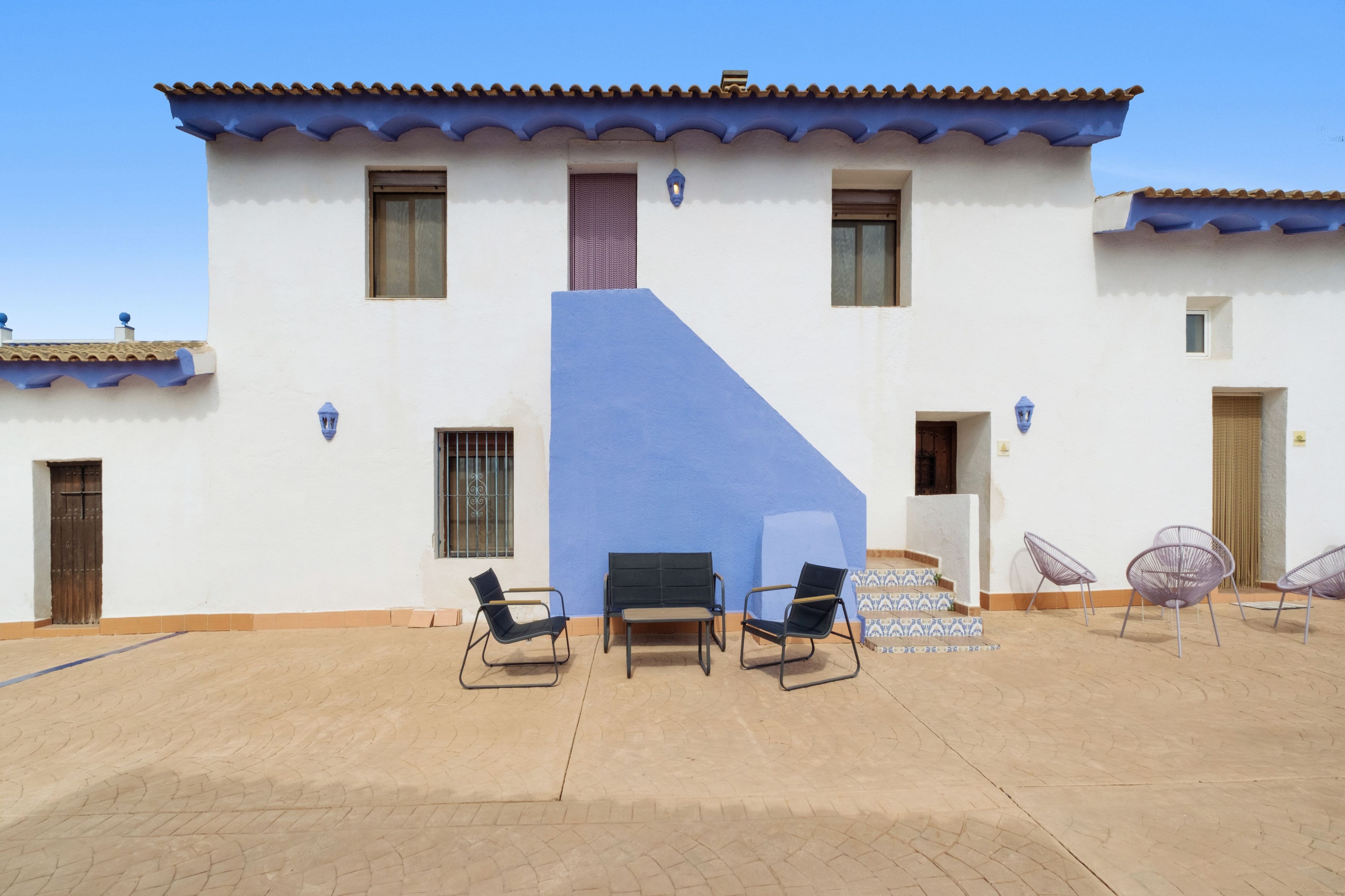 A building with a blue accent wall, a patio with chairs, and a tiled floor.