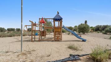 A playground with a slide, climbing structures, and a small shelter.