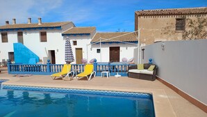 A pool area with lounge chairs, a table, and a small seating area. - Room 'Naranja' with Shared Pool, Wi-Fi and Air Conditioning (Lorca)