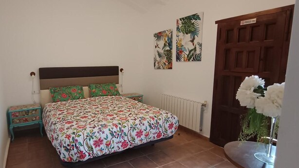 A bedroom with a bed, nightstands, a radiator, and a door. - Room 'Naranja' with Shared Pool, Wi-Fi and Air Conditioning (Lorca)