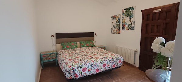 Een slaapkamer met een bed, nachtkastjes, een radiator en een deur.