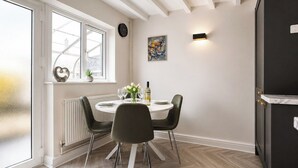 A dining area with a round table, black chairs, a potted plant, and a window with a view. - Beautiful Abode in The Bath Cotswolds (Frome)
