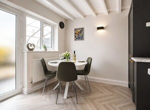 A dining area with a round table, black chairs, a potted plant, and a window with a view. - Beautiful Abode in The Bath Cotswolds (Frome)